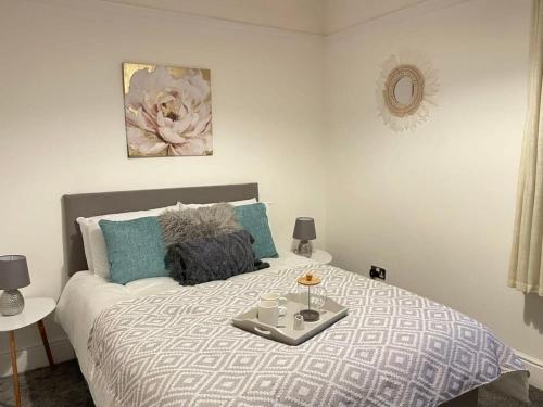 a bed with a tray with two cups on it at Cosy home with FREE PARKING and fast internet in Portsmouth