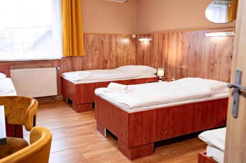 two beds in a room with wooden walls at Hotel Taurus in Ostrava