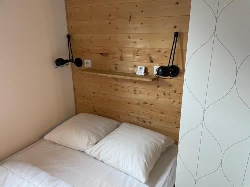 a bed in a room with a wooden wall at Charmant appartement 2 pièces - 4 personnes in Châtel