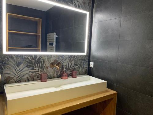 une salle de bain avec un lavabo et un miroir dans l'établissement Villa Le Patio Bleu au calme, piscine chauffée, centre ville, à Arès