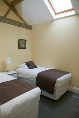 a bedroom with two beds and a skylight at Owls Hoot at Tove Valley Cottages in Towcester