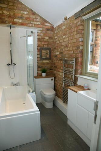 Owls Hoot at Tove Valley Cottages في توسيستر: حمام مع مرحاض وحوض استحمام ومغسلة