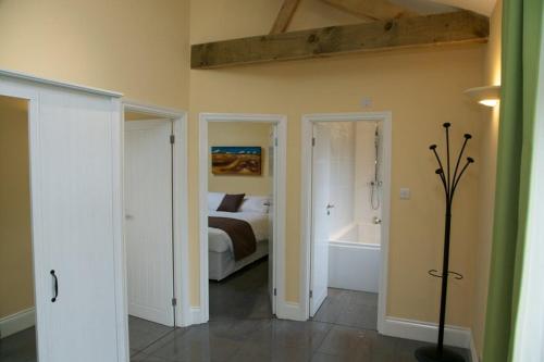 Owls Hoot at Tove Valley Cottages في توسيستر: غرفة نوم مع سرير وحوض استحمام