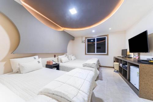 a hotel room with three beds and a flat screen tv at Number 25 Gyeongju City Hall in Gyeongju