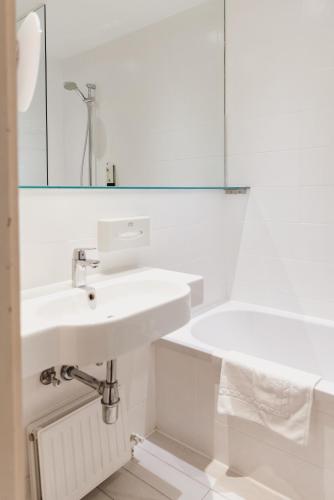a white bathroom with a sink and a mirror at Hotel Kaiserhof in Anif