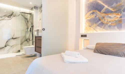 Un dormitorio con una cama blanca y una pintura en la pared en Apartamento para dos al lado de la Alhambra, en pleno centro, en Granada