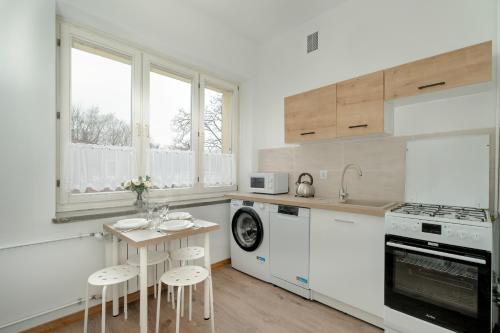 a kitchen with white cabinets and a table with stools at Cosy Studio in the Centre of Poznań with Balcony by Renters in Poznań
