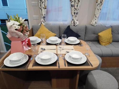 a table with plates and wine glasses on it at 3 Beds Sleeps 8 House Near California Cliffs Park in Norwich