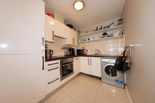 a kitchen with white cabinets and a washing machine at Chic & Radiant 1BD Flat near Dublin City Centre! in Dublin