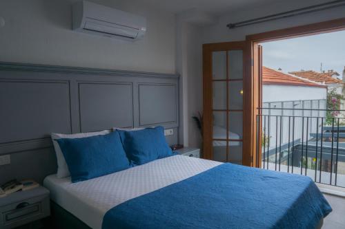 um quarto com uma cama com almofadas azuis e uma varanda em Laika konukevi em Seferihisar
