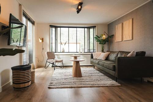 a living room with a couch and a table at Chalet op familiepark Veluws Hof op de Veluwe in Hoenderloo