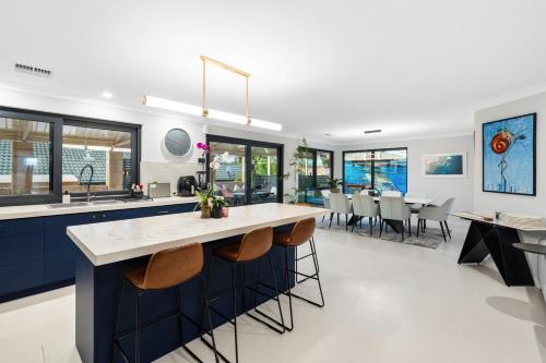 a kitchen with blue cabinets and a large island with stools at Luxury 5br villa with pool in Kinross