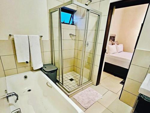 a bathroom with a shower and a bath tub at Luxurious Exclusive Home In A Golf Estate in Roodepoort