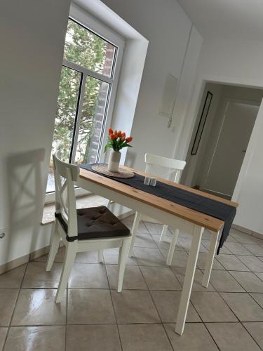 Apartment Gästehaus Tönisvorst في Tönisvorst: طاولة غرفة الطعام مع إناء من الزهور عليها