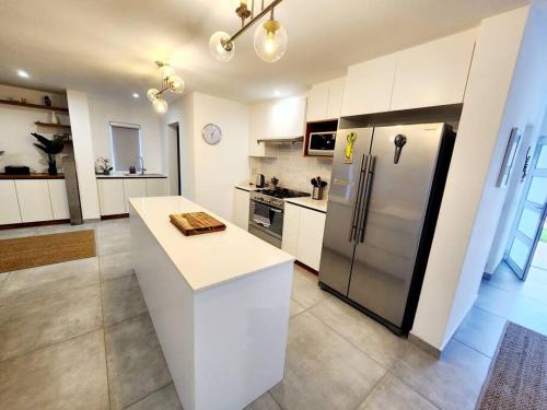 a kitchen with white cabinets and a stainless steel refrigerator at Sunshine Sally in St Helena Bay