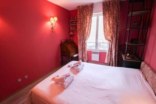 - une chambre rouge avec 2 serviettes sur un lit dans l'établissement Le BILLANCOURT comfortable, spacious and well-equipped apartment, à Boulogne-Billancourt