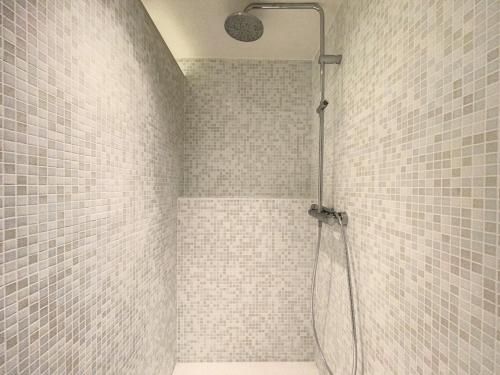 La salle de bains est pourvue d'une douche et de murs carrelés blancs. dans l'établissement Appartement 'Thibault' te Oostduinkerke - Bad, à Oostduinkerke