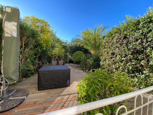 une terrasse en bois avec une table au milieu dans l'établissement Only 60m to the beach, 2 bedroom cozy apartment, 80m2 big garden, very central, à Cannes