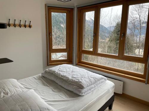 a bed in a bedroom with two windows at Charmant appartement 3 pièces - 6 personnes in Châtel