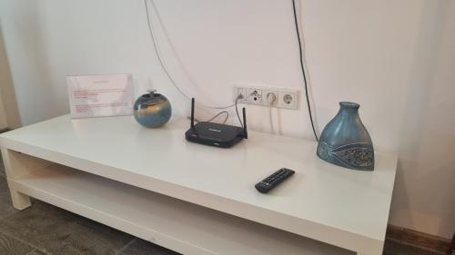 a white table with vases and a remote control on it at Airport Residence in Otopeni