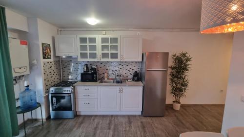 a kitchen with white cabinets and a stainless steel refrigerator at Airport Residence in Otopeni