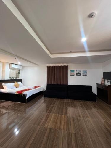 een slaapkamer met een bed en een bank in een kamer bij Island Wanderers Inn in Coron