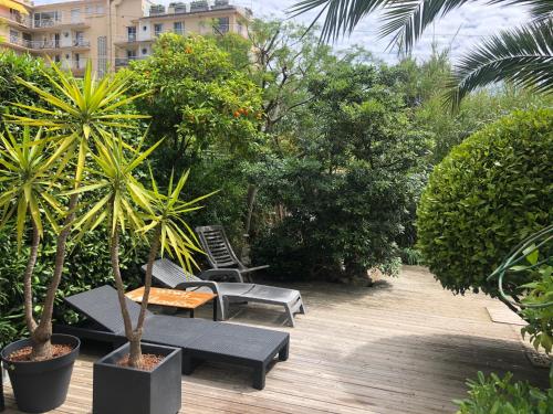 un patio avec une table, des chaises et des arbres dans l'établissement Only 60m to the beach, 2 bedroom cozy apartment, 80m2 big garden, very central, à Cannes