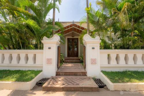 a white house with palm trees in front of it at Love Story Villas, Baga-Private Pool Villas in Arpora