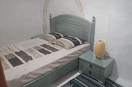 een slaapkamer met een bed en een vaas op een tafel bij Maison midoun a cote de la mer in Midoun