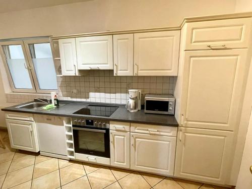 a kitchen with white cabinets and a sink and a microwave at Apartments im Herzen Lübecks in Lübeck