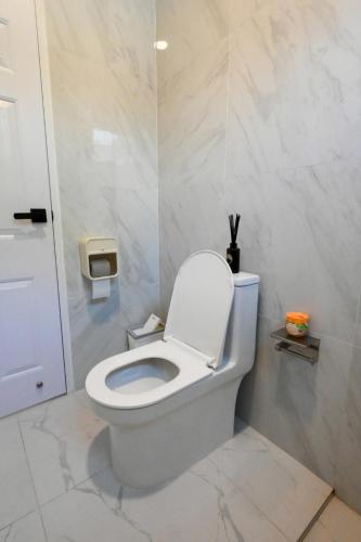 a white toilet in a bathroom with marble walls at Baan Khongkwan Pool villa Khaoyai Pakchong in Pak Chong