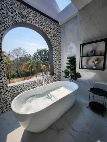 a white bath tub in a bathroom with a window at Baan Khongkwan Pool villa Khaoyai Pakchong in Pak Chong