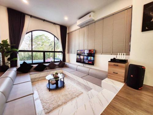 a living room with a couch and a large window at Baan Khongkwan Pool villa Khaoyai Pakchong in Pak Chong