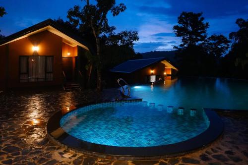 a swimming pool in front of a house at night at Vyna Hillock Resort and Spa in Vythiri