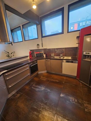 a large kitchen with windows and stainless steel appliances at Le loft in Landerneau