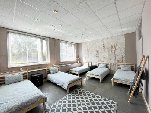 een kamer met 3 bedden en 2 ramen bij Hostelis R27 in Aizpute