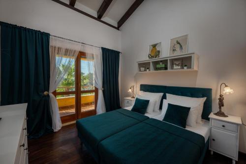 a bedroom with a green bed and a balcony at Villa Barotul with pool in Mrljane