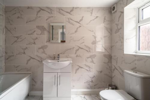 a white bathroom with a sink and a toilet at England's Cozy 1-Bed room Room 1 in Manchester