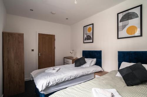 a bedroom with two beds with blue chairs at England's Cozy 1-Bed room Room 1 in Manchester