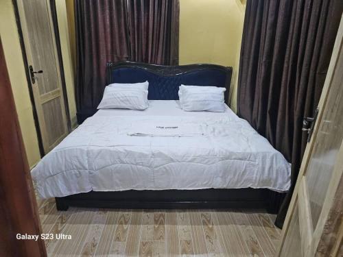 un letto con lenzuola e cuscini bianchi in una camera da letto di A-Plus Apartment ad Asi
