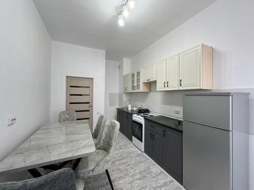 una cucina con mobili bianchi e un tavolo con sedie di Квартира a Türkistan