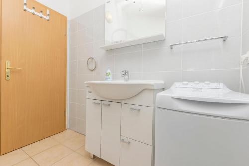 a white bathroom with a sink and a mirror at Apartments Rosanda in Pirovac