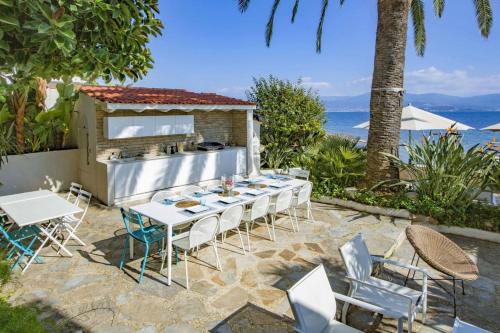 un patio avec une table et des chaises et l'océan dans l'établissement The ideal waterfront vacation home in Ajaccio, à Ajaccio
