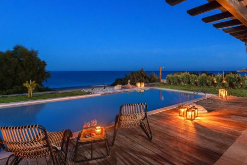 a swimming pool with two chairs and a table on a wooden deck at Villa Sevil in Lachania