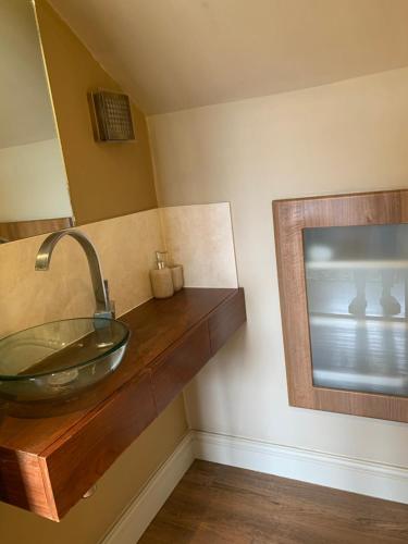 a bathroom with a glass sink and a mirror at First floor Pad Carterton near Burford in Shilton