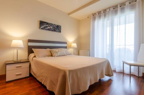 a bedroom with a bed and a large window at FLATSELECT Decanelas in Portonovo