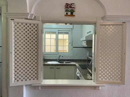 eine Küche mit einem Waschbecken und einem Spiegel in der Unterkunft PRECIOSOS APARTAMENTO DE DOS DORMITORIOS in Ayamonte