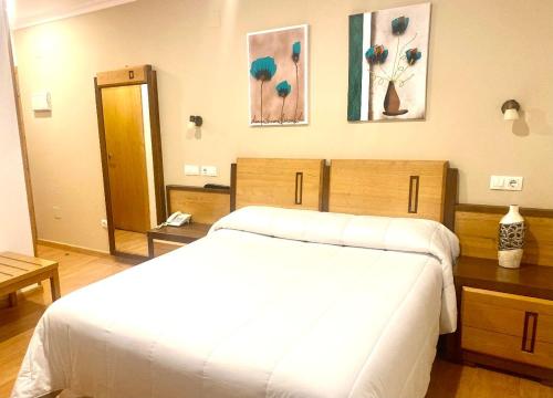 a bedroom with a large white bed and paintings on the wall at Hotel Spa Galatea in Burela de Cabo