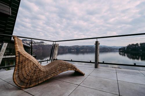 a wicker chair sitting on a balcony overlooking a lake at NOI Resort SPA - woda i las in Tęgoborze