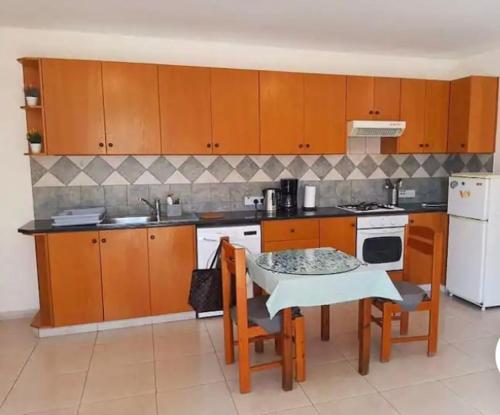 una cocina con armarios de madera y una mesa con sillas. en Bright One Bedroom Apartment in Paphos area en Pafos